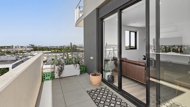 A balcony with a city view, potted plants, and a seating area with a sofa. - Bright City-view Retreat in the Heart of Preston (Melbourne)