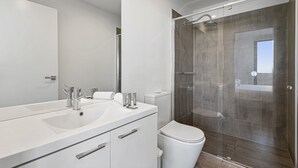 A modern bathroom with a large mirror, two sinks, a toilet, and a glass-enclosed shower. - Bright City-view Retreat in the Heart of Preston (Melbourne)