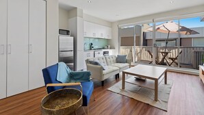 A modern living room with a sofa, a dining table, and a kitchen area. - Stylish North Melbourne Stay (Melbourne)