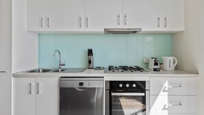 A modern kitchen with white cabinets, a dishwasher, an oven, a sink, and a gas stove. - Stylish North Melbourne Stay (Melbourne)