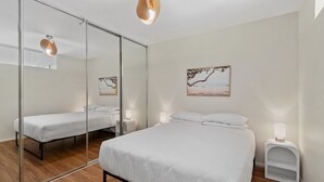 A bedroom with a large bed, a smaller bed, a mirror, and two wall-mounted lamps. - Stylish North Melbourne Stay (Melbourne)