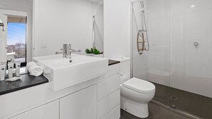 A modern bathroom with a double sink vanity, a toilet, and a glass-enclosed shower. - A Taste of Paradise in Inner City Suburbia (Melbourne)