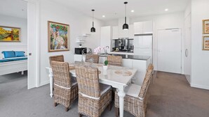 A modern kitchen with white cabinets, a central island, and black pendant lighting. - A Taste of Paradise in Inner City Suburbia (Melbourne)