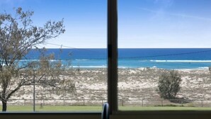 A view from inside a building, looking out to a beach with a clear sky. - Beachfront Studio With Balcony & Stunning Views (Gold Coast)