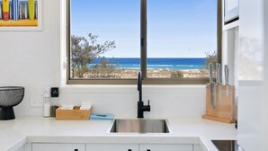 A kitchen with a large window offering a view of the beach. - Beachfront Studio With Balcony & Stunning Views (Gold Coast)
