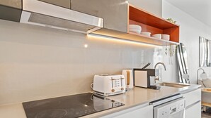 A modern kitchen with a built-in stove, a toaster, and a dishwasher. - Stylish West End Stay With Rooftop Pool & BBQ (Brisbane)