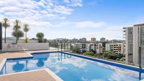 A rooftop swimming pool with a clear view of surrounding modern buildings and palm trees. - Stylish West End Stay With Rooftop Pool & BBQ (Brisbane)
