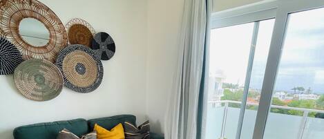 Una sala moderna con un sofá color turquesa, un reposapiés a juego y arte decorativo de fibra en la pared.