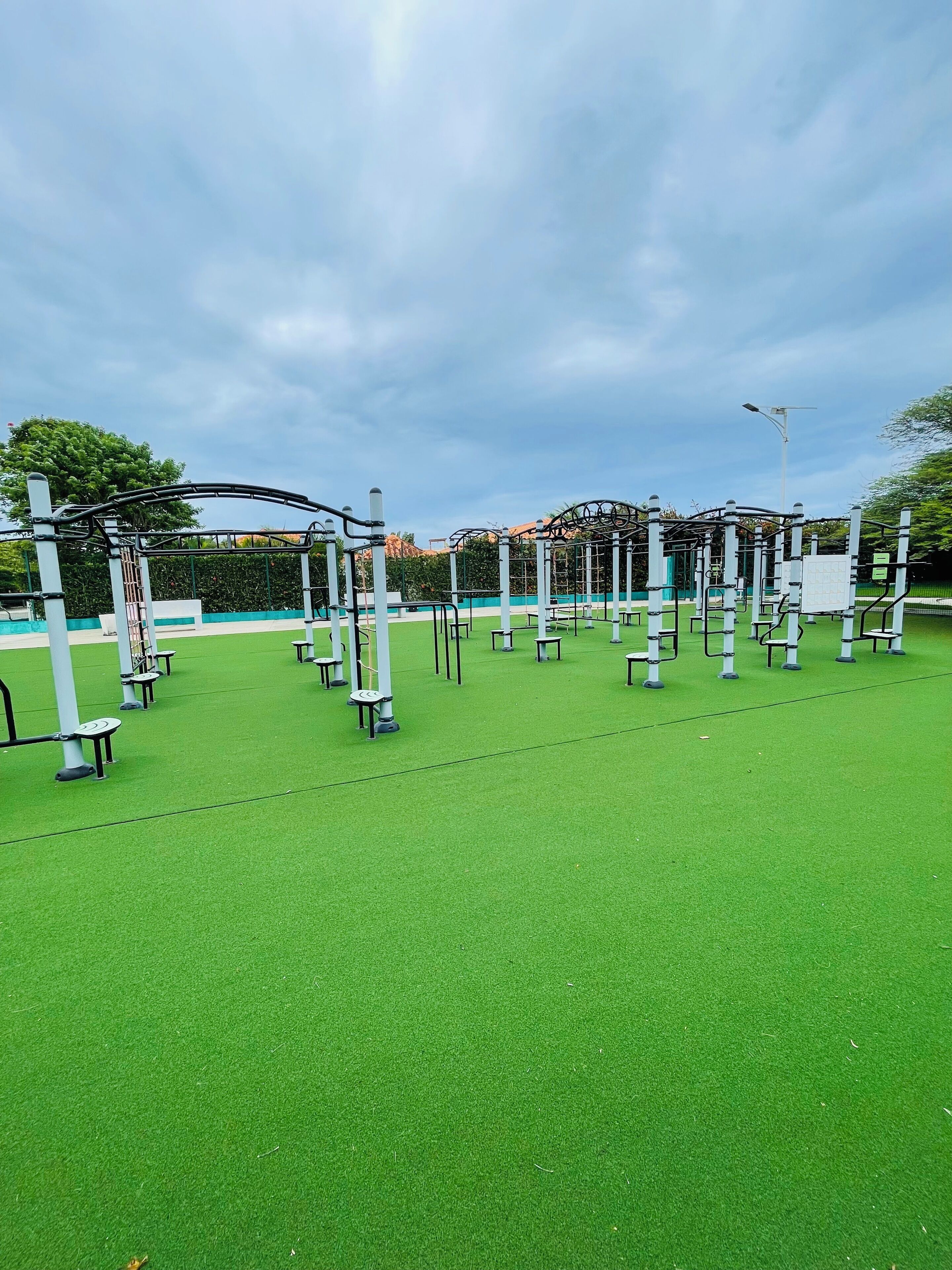 An outdoor gym area with exercise equipment and artificial turf.
