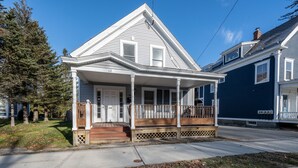A two-story house with a front porch, a garage, and a driveway. - Cozy Condo in Downtown Ludlow | Walk to Dining (Ludlow)