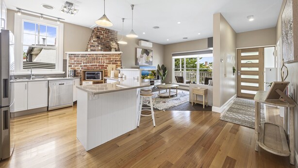 A modern kitchen with white cabinetry, a brick fireplace, and a large island. - Lovely 3-bed With Alfresco Dining in Prime Suburb (Ballarat)