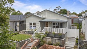 A two-story house with a front porch, a small backyard with a lawn and garden beds, and a brick staircase leading to the front door. - Lovely 3-bed With Alfresco Dining in Prime Suburb (Ballarat)