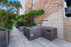 A modern outdoor seating area with a stone bench and a planter with green foliage. - Charming 1-bed Apartment With a Balcony (Melbourne)