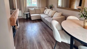 Una sala de estar acogedora con techo de madera, un sofá, una mesa de comedor y un espejo grande.