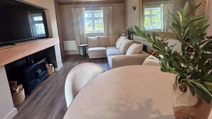 Una sala de estar acogedora con sofá, televisión, chimenea y mesa de comedor.