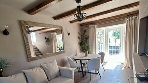 Un salón amplio con techo de madera, un sofá, una mesa de comedor con sillas y un espejo grande en la pared.