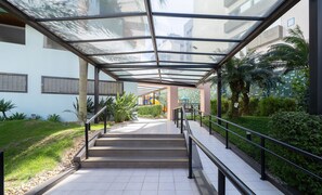 A covered outdoor staircase leading to a building with a playground visible in the background.
