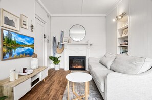 Uma sala de estar moderna com lareira, uma pintura grande e um espaço de estar acolhedor.