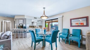 A modern living room with a dining area, a kitchen in the background, and a large window providing natural light. - HavaHappyStay | Near Lake and Golf~RV/Boat Parking (Lake Havasu City)
