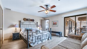 A bedroom with a bed, bedside lamps, a ceiling fan, and a view of the patio through a glass door. - HavaHappyStay | Near Lake and Golf~RV/Boat Parking (Lake Havasu City)