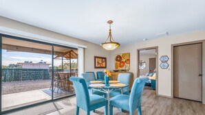 A modern living room with a large glass door leading to a patio, a round table with chairs, and a ceiling light fixture. - HavaHappyStay | Near Lake and Golf~RV/Boat Parking (Lake Havasu City)