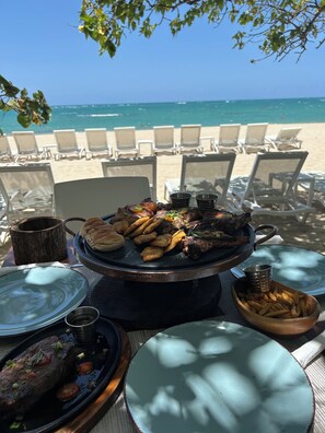 A beachside dining setup with a grill, plates, and chairs. - Fantastic apartment with AC in Green one, Playa Dorada (Playa dorada)