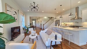 A modern kitchen with a central island, stainless steel appliances, and pendant lighting. - Grant Park Retreat - Steps to Zoo, & Great Eats (Atlanta)