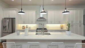 A modern kitchen with white cabinets, stainless steel appliances, and pendant lighting. - Grant Park Retreat - Steps to Zoo, & Great Eats (Atlanta)