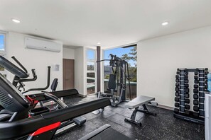 Une salle de sport équipée de tapis de course, d’appareils de musculation et d’un banc.