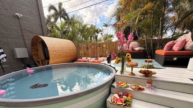 Ein Whirlpool mit Holzfass, Sitzgelegenheiten im Freien und einer Obstauslage.