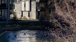 A modern multi-story building with a stone facade, a flat roof, and a small courtyard. - Luxury retreat: hot tub, steam shower, 2-bed 2-bath on the Blue River. (Silverthorne)