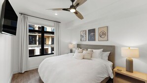 A hotel room with a large bed, a ceiling fan, a TV mounted on the wall, and artwork on the wall. - Luxury retreat: hot tub, steam shower, 2-bed 2-bath on the Blue River. (Silverthorne)
