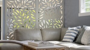 A living room with a grey sofa, striped pillows, and a woven basket on the coffee table. - Coastal Retreat on Hazel - Lakes Entrance Getaway (Kalimna)