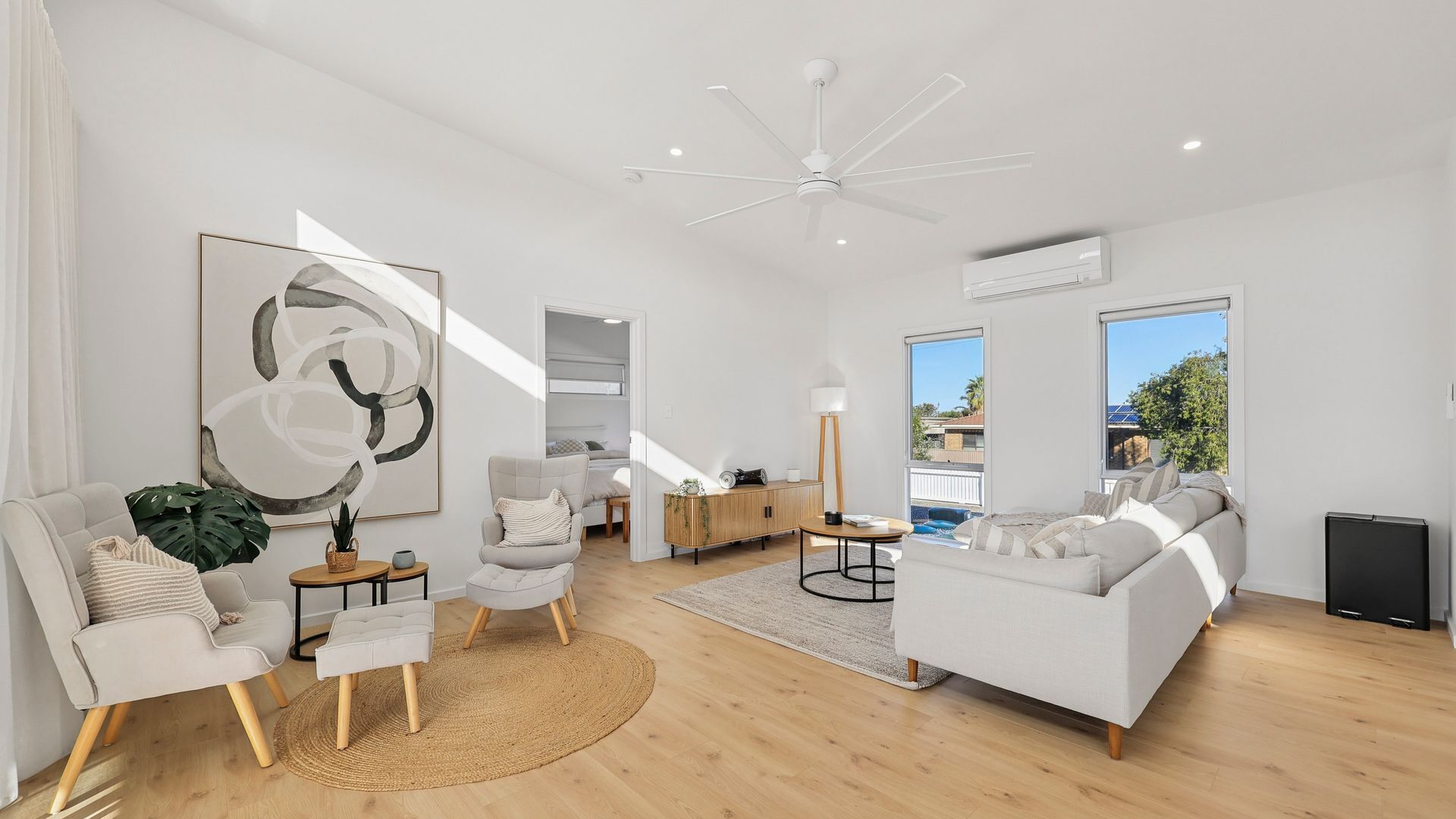 A modern living room with a sofa, armchair, and a ceiling fan.