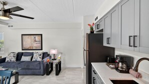 A modern kitchen with grey cabinets, a black refrigerator, and a coffee maker on the counter. - Your Gulf Coast Escape in Madeira Beach (St. Petersburg)