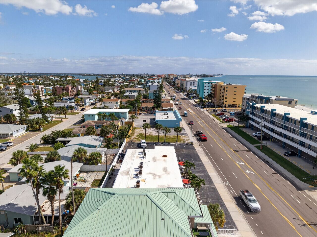 A coastal cityscape with a wide road, buildings, and a view of the ocean.