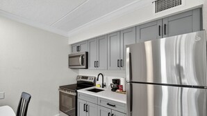 Una cocina moderna con gabinetes grises, un refrigerador de acero inoxidable, un microondas, un horno y un fregadero.