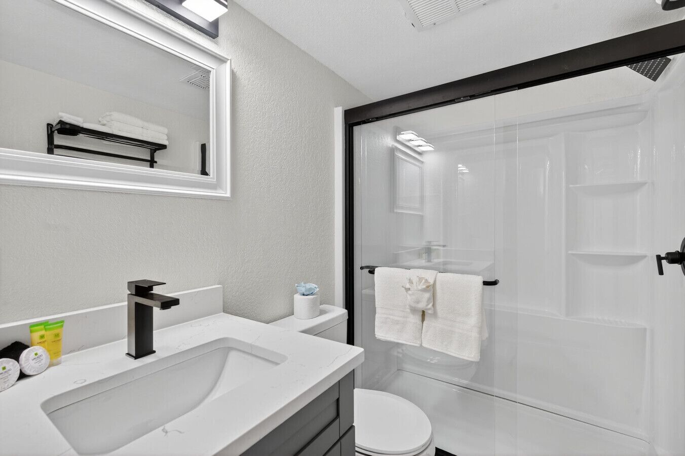 A modern bathroom with a large sink, mirror, and a glass shower enclosure.