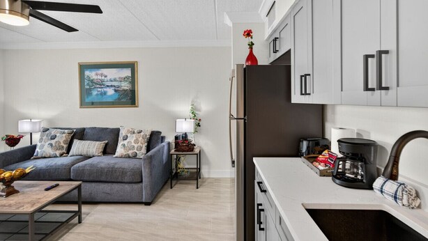 Ein modernes Wohnzimmer mit einem grauen Sofa, einem Couchtisch und einem Bild an der Wand.