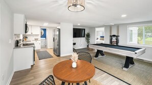A modern kitchen with white cabinets, a built-in microwave, and a dining area with a wooden table and chairs.