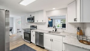 A modern kitchen with white cabinets, stainless steel appliances, and a granite countertop.