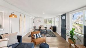 A spacious living area with a sofa, armchair, and dining table.