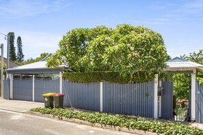 A residential area with a blue fence, a covered porch, and a small garden area.