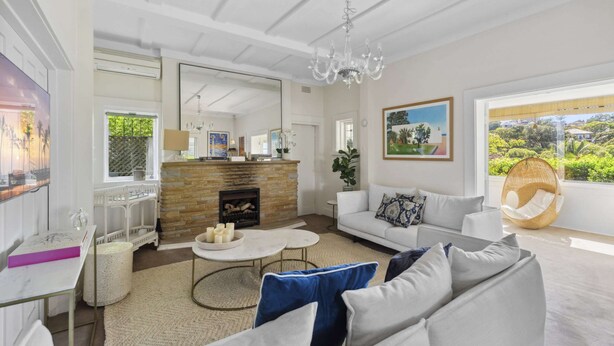 A spacious living room with a fireplace, a sofa, a coffee table, and a hanging chair. - Poolside Stay - Close to Taronga Zoo & Luna Park (Sydney)
