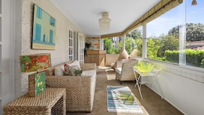 A sunlit room with a sofa, chairs, a small table, and a view of greenery outside. - Poolside Stay - Close to Taronga Zoo & Luna Park (Sydney)