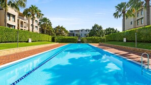 A swimming pool with a clear blue water, surrounded by a brick walkway and bordered by well-maintained hedges. - Elegant Stay in Balmain With Pool Access (Sydney)