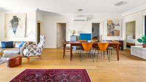 A spacious living area with a sofa, a patterned armchair, a dining table with chairs, and a red rug. - Elegant Stay in Balmain With Pool Access (Sydney)