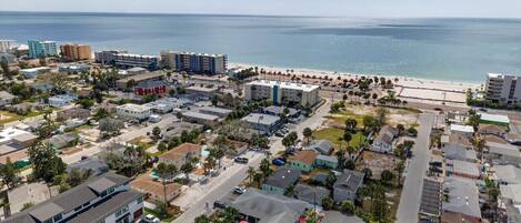 An aerial view of a coastal town with a beach, residential buildings, and a marina.