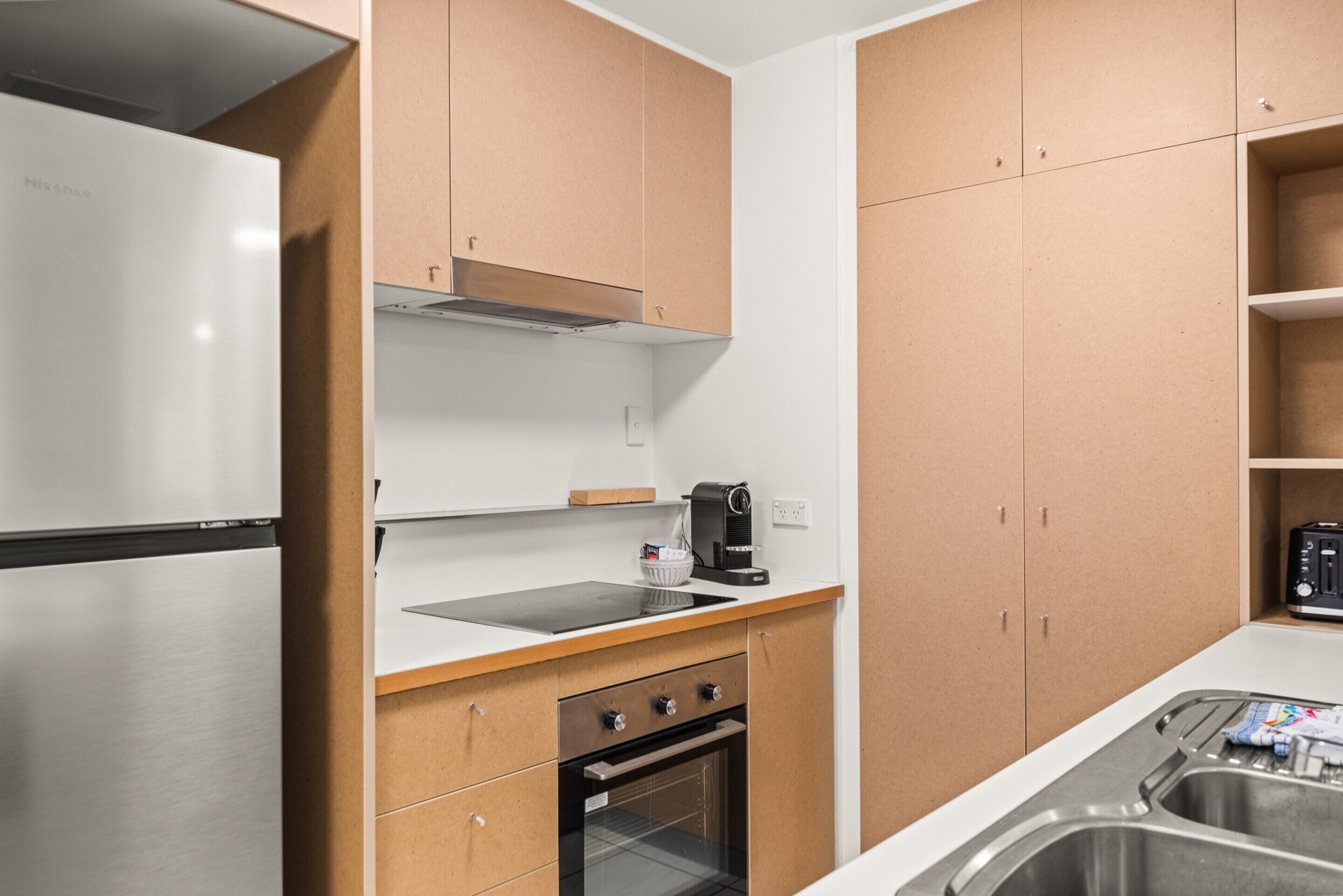 A compact kitchen with a stainless steel refrigerator, a coffee maker, a toaster, and a sink.