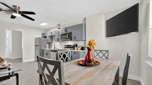 A modern kitchen with grey cabinets, a microwave, and a dining area with a wooden table and chairs.